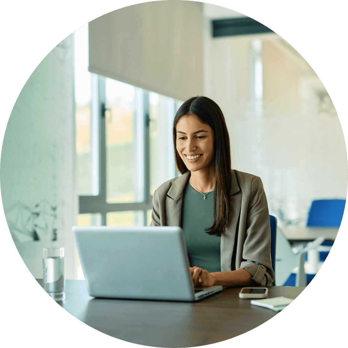 A woman smiling and typing on a laptop