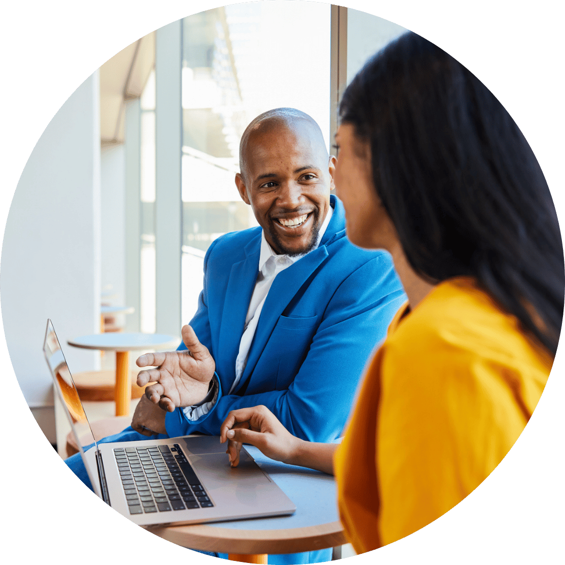 A man and woman talking around a laptop