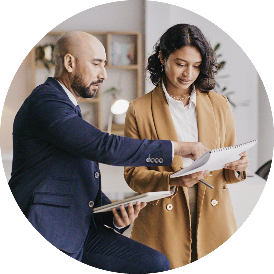 Two coworkers discussing over a notebook