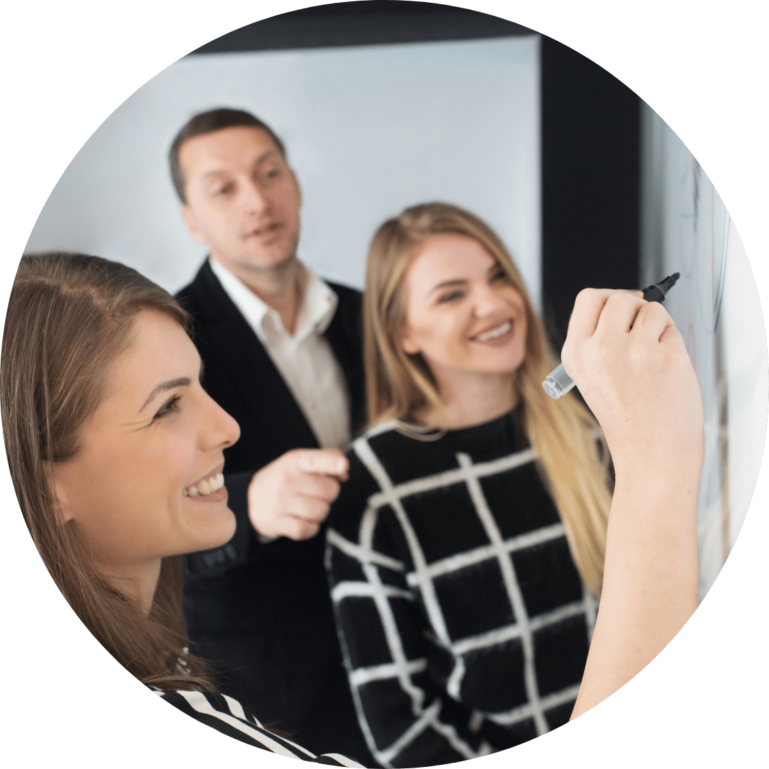 A woman writing on a whiteboard with coworkers