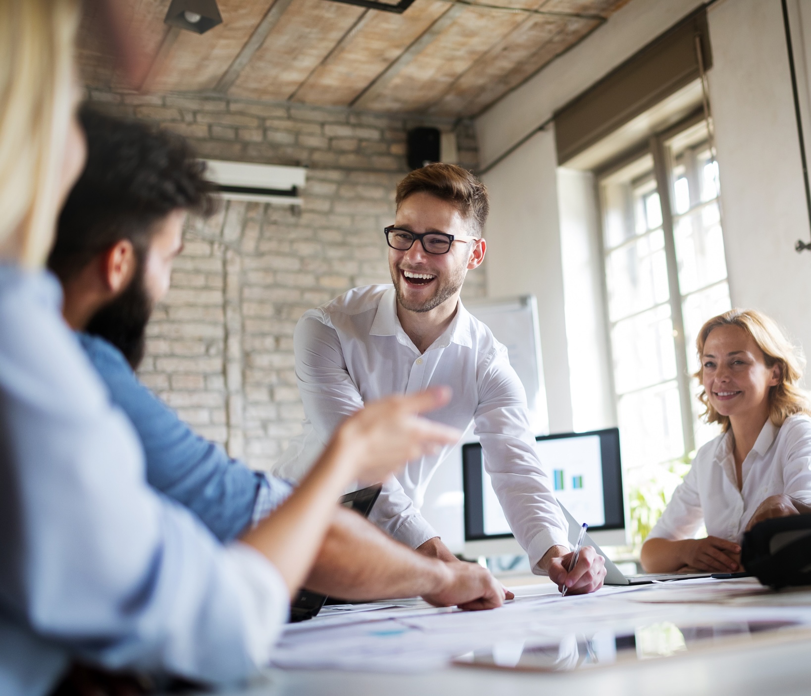 A man smiling and talking to a group at an office