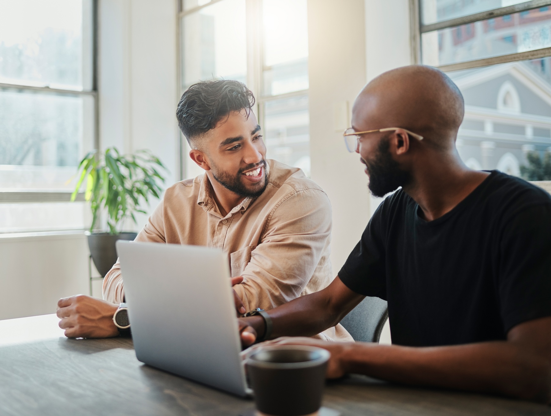 Two men talking around a laptop