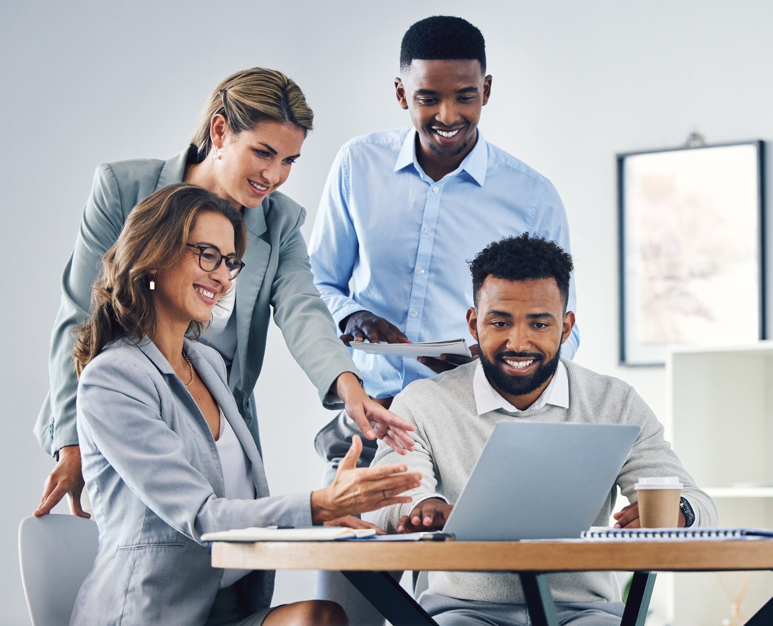 Four coworkers gathered around a laptop
