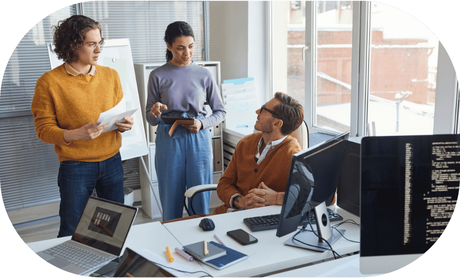 Three coworkers chatting at a desk