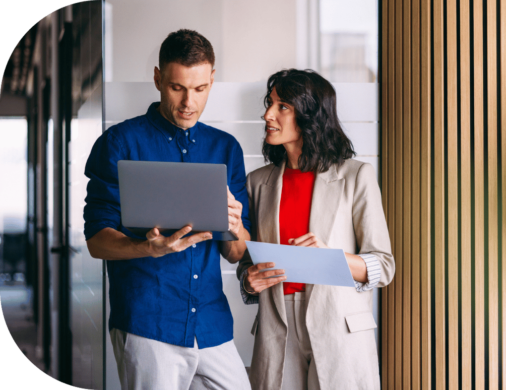 Two coworkers talking over a laptop