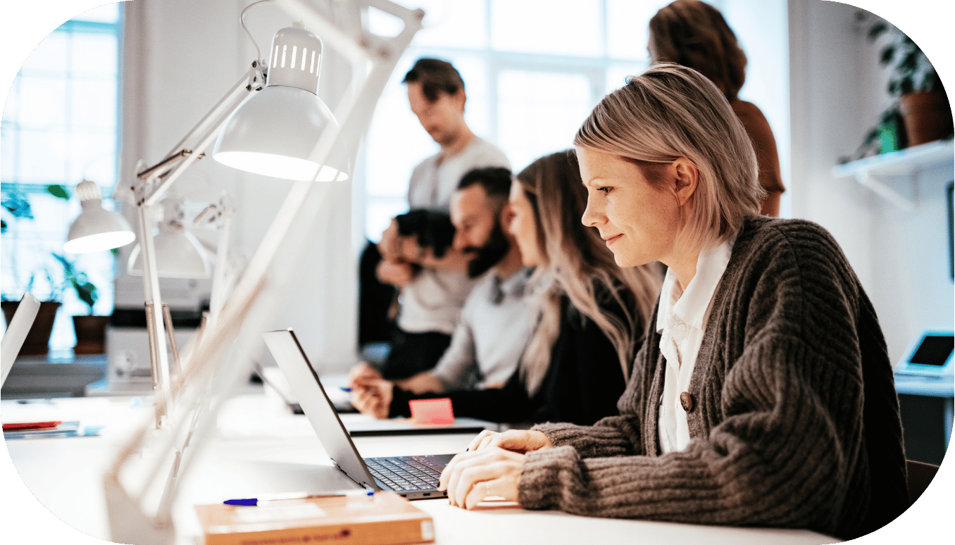 A woman working on her computer in a busy office