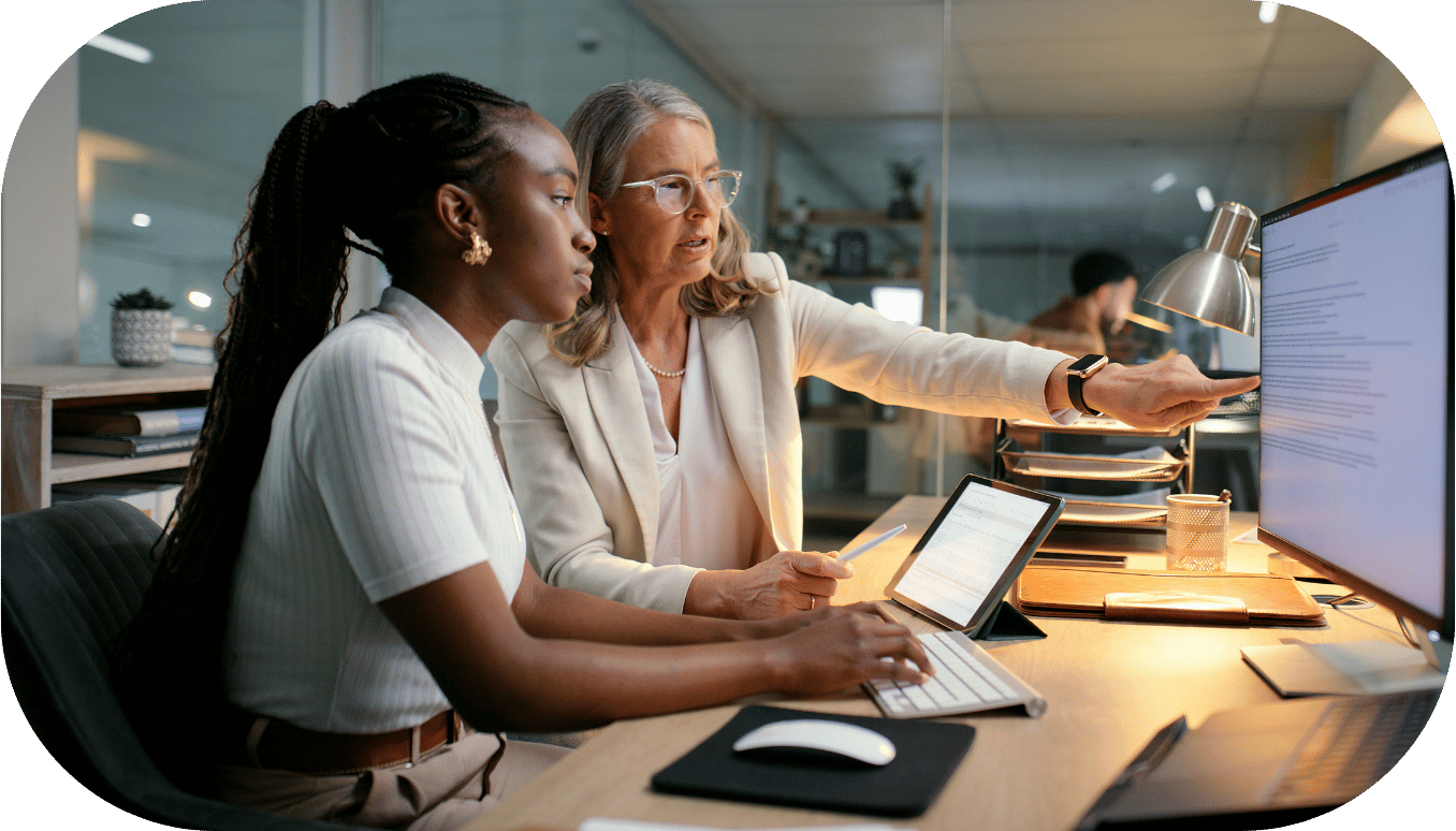 Two women pointing at a desktop