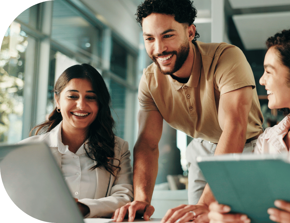 Three coworkers smiling and looking at a laptop