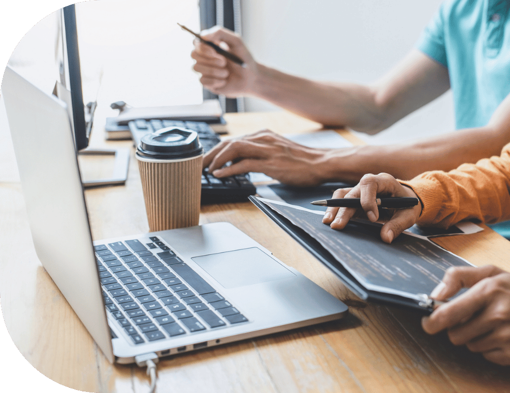 A closeup of two people working on a laptop