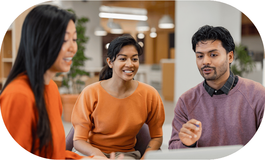 Three coworkers talking and pointing to a laptop